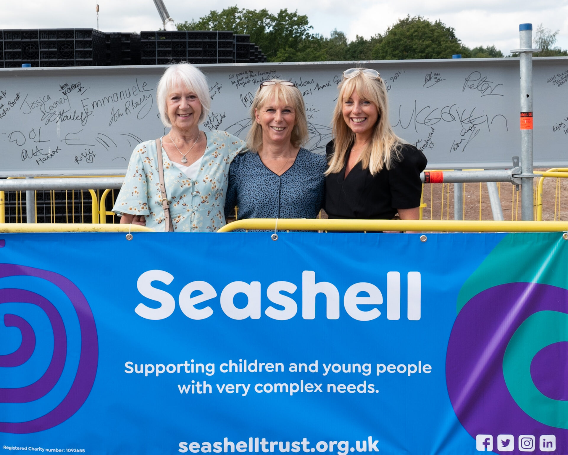 three women stood smiling behind blue Seashell banner